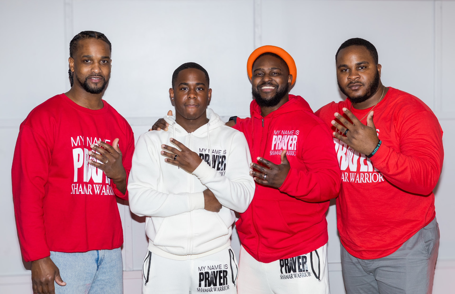 Four watchmen standing together in red and white My Name Is Prayer Shamar Warrior tees and hoodie sets