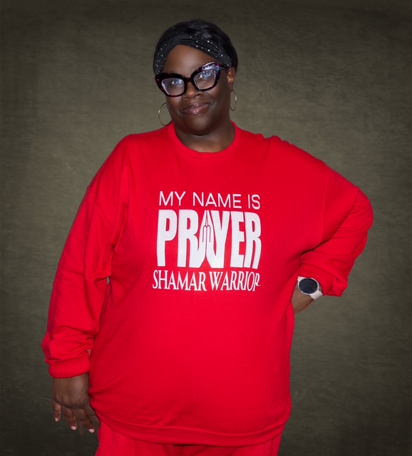 A woman wearing a red My Name Is Prayer Shamar Warrior sweatshirt